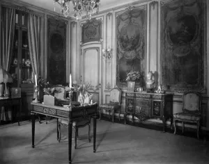 room with desk, chairs, paintings in panels, glass case